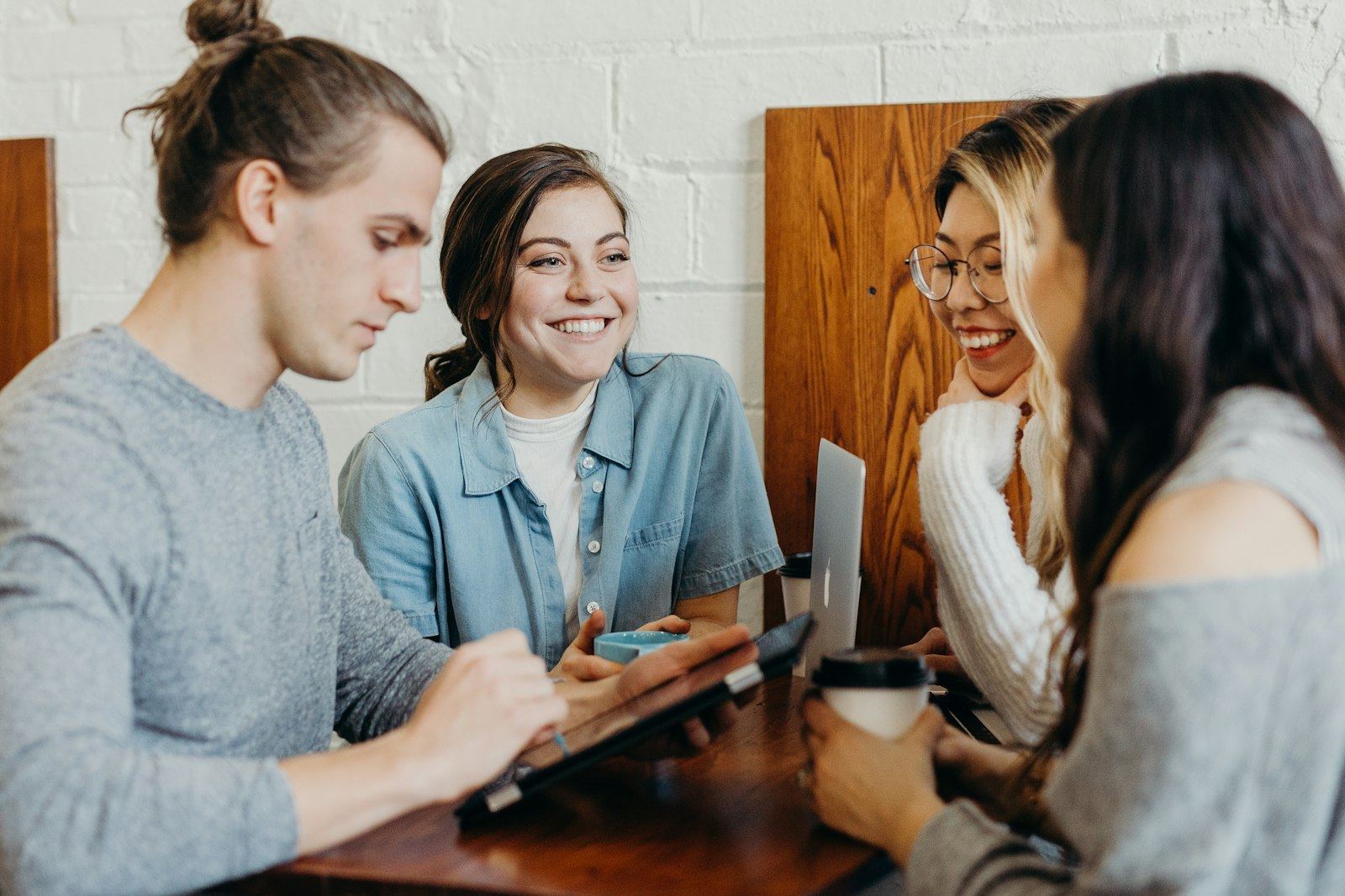 Four students around a table, one holding a tablet